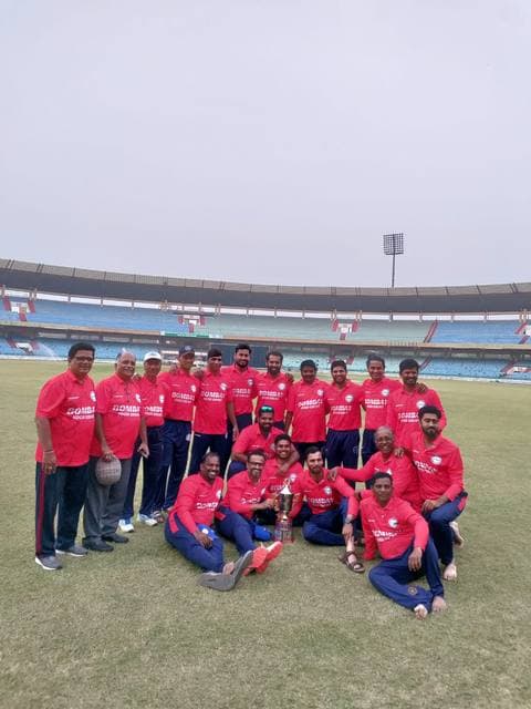 A team in red kit posed in front of a stadium stand