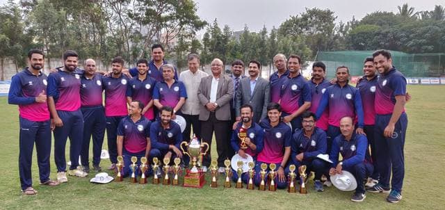 A team in pink and navy kit with trophies and officials behind