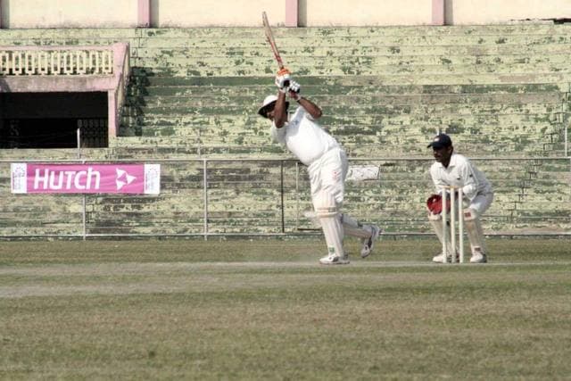 A batsman playing a shot with the wicketkeeper behind him