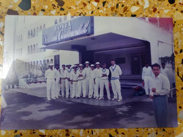A team in whites outside a hotel entrance in an old photograph