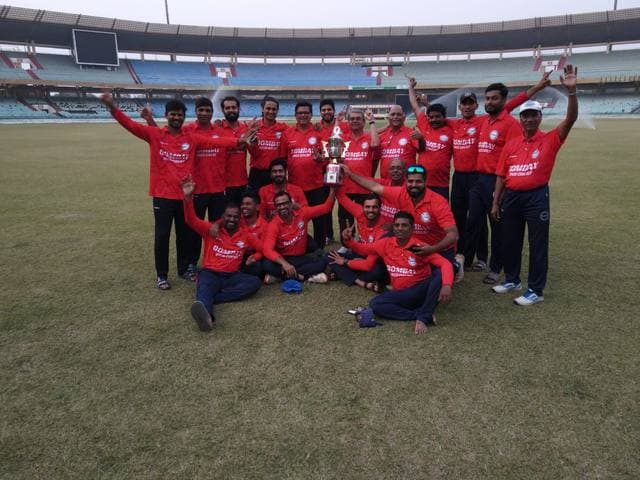 A team in red kit cheering in a stadium, holding a cup