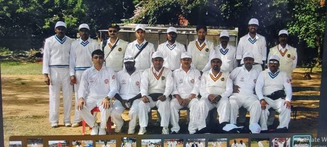 A team in whites seated and standing in rows