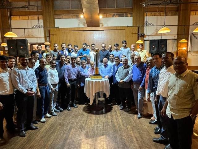 A large gathering around a trophy on a table in a hall