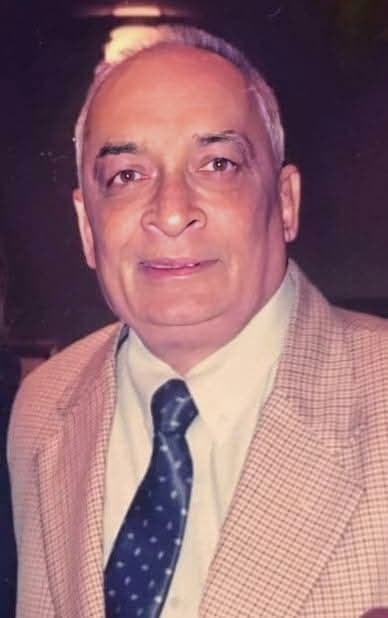 The late Adv. Vijay Tulpule, formal portrait in a check jacket and tie